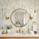 Modern bathroom interior with large round mirror, gold fixtures and eucalyptus leaf wallpaper accent wall, modern bathroom interior with large round mirror, gold fixtures and eucalyptus leaf wallpaper accent wall