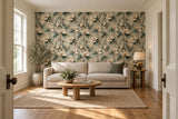 Muted magnolia wallpaper behind a low linen sofa, with white side walls, oak furniture and a dusty-green cushion.