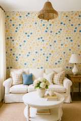 Floral cornflower parade wallpaper with yellow and blue flowers, covering a wall, featuring a natural fiber chandelier.
