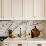 Carrara Veil Wallpaper with marble pattern, styled with a sink, rosemary, lemons, bottle, and cutting board.
