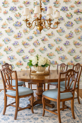 Floral teacup garden wallpaper featuring blue and peach blossoms, displayed on a wall behind a dining set.
