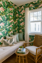 Palm Mirage wallpaper with a tropical floral pattern on the wall of a cozy reading nook.