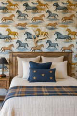 Run Wild Wallpaper with a horse pattern, featuring brown, grey, and gold colors, on a textured wall above a wooden headboard.
