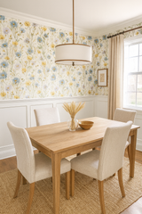 Floral Meadow Flicker Wallpaper with yellow and blue flowers covering the walls above white wainscoting in a dining room setting.