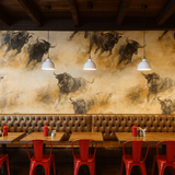 La Matador wallpaper featuring a herd of bulls, with a beige and brown color scheme, above a leather booth in a restaurant.
