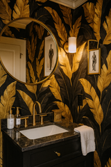 Golden tropic wallpaper with black background and gold leaf pattern, decorating a bathroom wall with a round mirror.