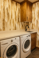 Featherfall wallpaper featuring gold and beige feathers by wallpaper direct, shown in a laundry room setting.