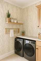 Neutral-toned wallpaper with stylized wheat pattern, a prairie whisper design, with wooden shelf, drying rack, and laundry machines.
