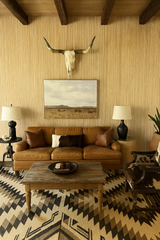 Textured bamboo wallpaper with a vertical striped pattern, underneath wooden ceiling beams and a cow skull.