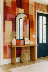 Heatmap wallpaper with a geometric block pattern in orange and red hues, with a minimalist console table and mirror.
