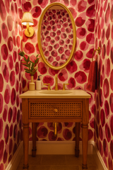 Rose Ember wallpaper, featuring a red and pink watercolor dot pattern, covering the walls of a small bathroom.
