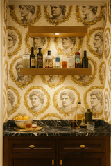 Laurel Imperium Wallpaper with Roman-inspired head and wreath pattern on a light background.
