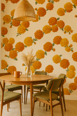 Orange floral wallpaper with green leaves, over a beige background, forming a stylish marigold pattern.
