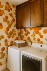 Floral marigold wallpaper with an orange botanical pattern, covering walls and cabinets.