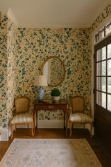 Floral wallpaper with a green and brown pattern on a tan background, covering the walls of an entryway.
