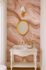 Pink and gold Rose Quartz Luxe Wallpaper with a marble pattern, covering the wall behind a bathroom sink.
