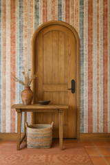 Patterned wallpaper with stripes of orange and blue with geometric designs, in front of a wooden arched doorway.
