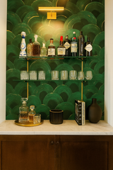 Green and gold Verdant Echo wallpaper, a semicircular pattern background with a decorative display shelf.