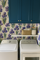 Floral wallpaper with iris pattern, against blue cabinets, arranged in a laundry room.