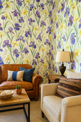 Floral wallpaper with irises from Bayou Bloom, covering a corner with purple and yellow flowers against a cream background.

