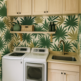Palm leaf patterned wallpaper with green fronds, and neutral background, displayed in a laundry room setting.
