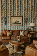 Diamond Drift wallpaper in blue and orange with diamond pattern against a textured wall.
