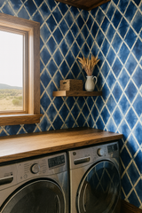 Diamond patterned wallpaper with blue shibori print, with wheat stalks and basket on a wooden shelf.
