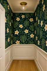 Monstera Noire Wallpaper featuring tropical leaves and floral pattern in a small room setting.
