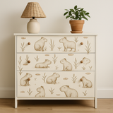 Capybara Club wallpaper with a beige animal pattern, shown on a dresser with a lamp and potted plant.
