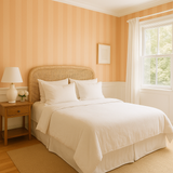 Peach blush plains wallpaper with vertical stripes, textured finish, decorating a bedroom interior.