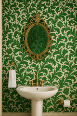 Green floral tapestry wallpaper with an ornate mirror above a white porcelain sink.