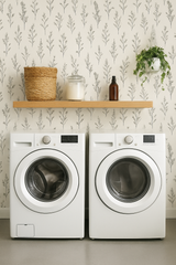 Botanical linework wallpaper with leafy fern pattern, decorative shelf, laundry machines, and potted plant.
