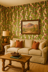 Cactus patterned wallpaper with pink fruit by Wallshoppe, covering the walls around a couch with southwest desert artwork.
