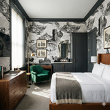 Patterned wallpaper with architectural drawings on a text background, showing a bedroom.
