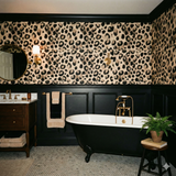 Leopard print Raw Aperture Wallpaper with black wainscoting and gold accents.