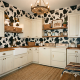 Oxenveil Wallpaper with a cow print pattern, covering the laundry room walls behind the white cabinets.
