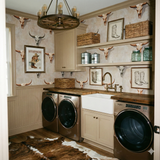 Patterned wallpaper depicting steer skulls and cowboy themed items, in a vintage western style.
