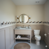 Harlow Parade Wallpaper with dog pattern over painted wainscoting and round mirror.
