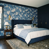 Blue floral Arbor Row Wallpaper featuring white blossoms and green leaves.