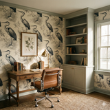 Magnolia Marsh wallpaper with a heron pattern, styled in a traditional office with a brown desk and built-in shelves.
