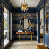 Nocturne Range wallpaper with blue and gold mountain pattern on the wall, styled in an entryway with a console table.
