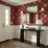 Garnet needlepoint medallion wallpaper with damask pattern, set above white wainscoting, in a well lit foyer.
