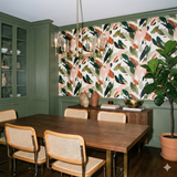 Verdance Etude wallpaper with a brushstroke leaf pattern, accenting a dining room with green walls and wood furniture.
