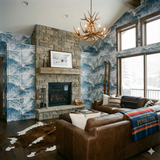 Blue and white wallpaper depicting snowy mountains, unbranded, covering an entire living room with a stone fireplace.