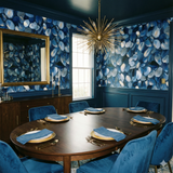 Midnight Littoral wallpaper with a blue abstract pattern, above wainscoting, next to a gold mirror.