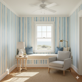 Striped wallpaper by Seabrook with blue, beige, and white vertical pattern in a cozy room setting.
