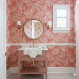 Palm leaf wallpaper with coral background, from Caldera, with a stylized, tropical pattern and a traditional style.

