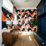 Abstract coral and navy wallpaper with organic shapes, by unknown brand, creating a bold and modern focal point in a hallway.