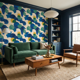 Abstract patterned wallpaper by York Wallcoverings featuring blues, greens, and yellows, styled in a modern living room.
