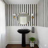 Black and white striped Cortez Stripe Wallpaper with black vertical stripes and gold framed mirror.
